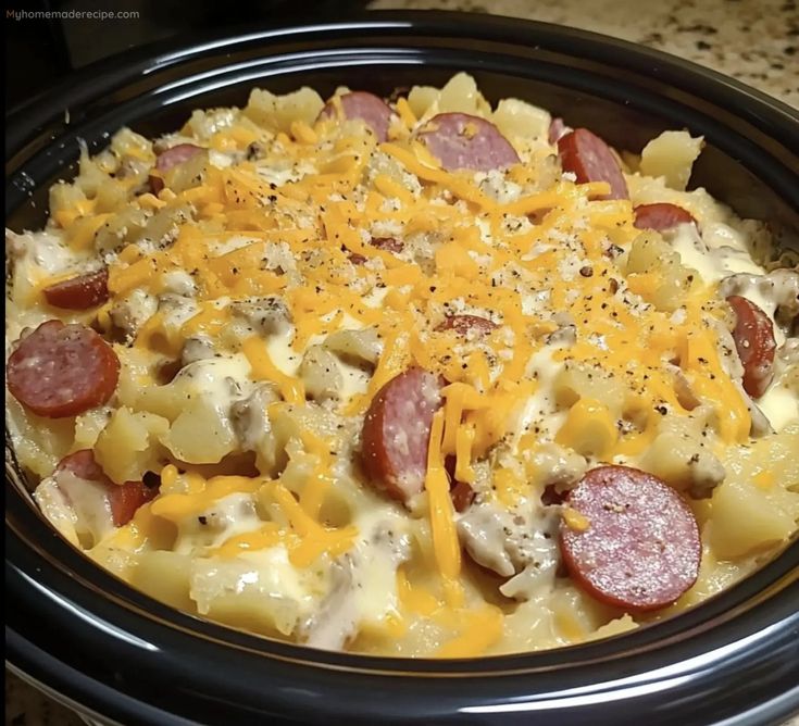 a crock pot filled with macaroni and cheese, pepperoni and sausage