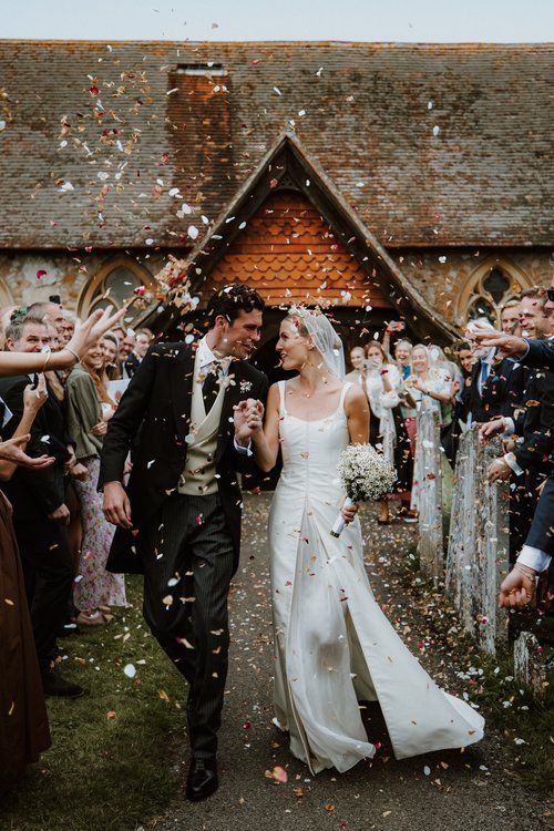 a newly married couple walking down the aisle as confetti is thrown around them