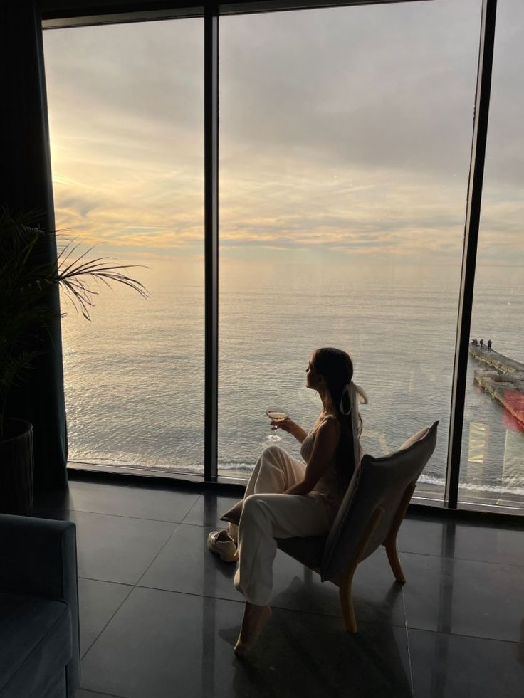 a woman sitting in a chair looking out at the ocean