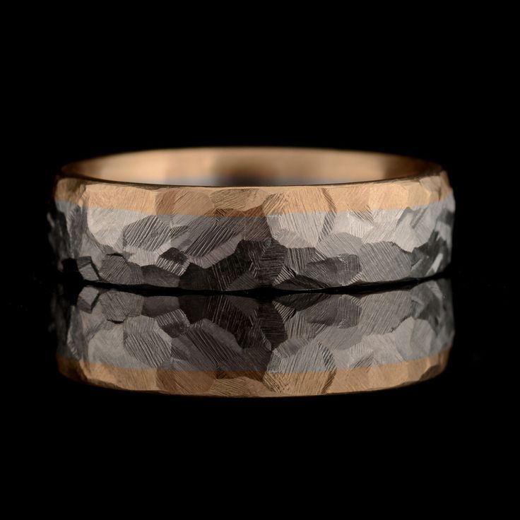 a wedding band made with gold and silver inlays, on a black background