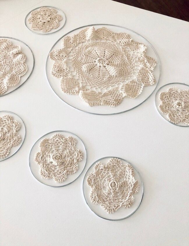 six crocheted coasters are arranged on a white tablecloth with lace doily