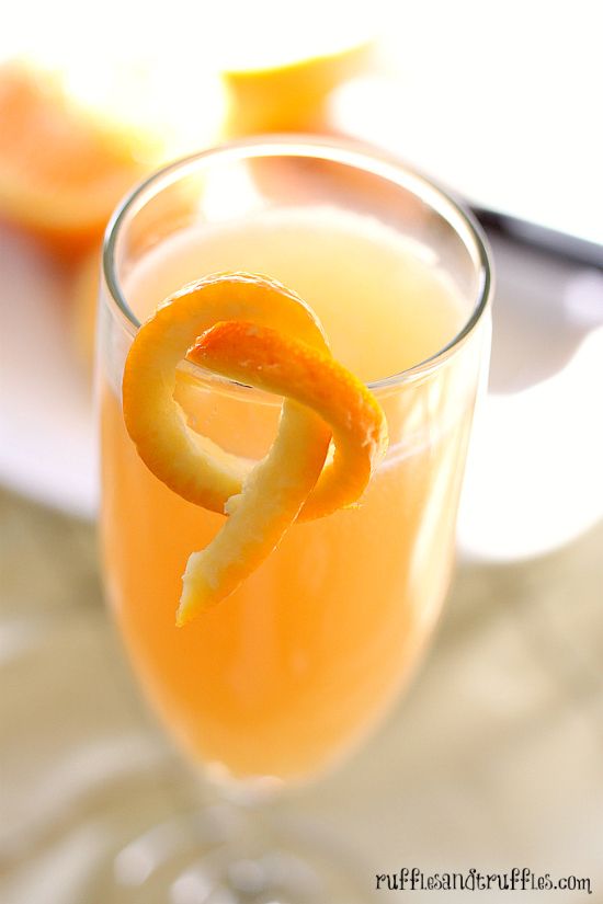 a close up of a drink in a glass with an orange peel on the rim