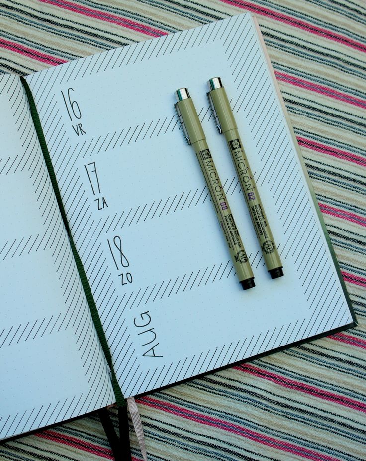 two pens sitting on top of an open notebook