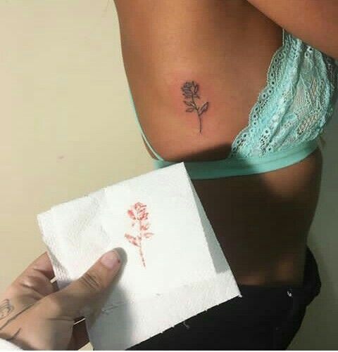 a woman with a small tattoo on her stomach holding a piece of paper in front of her back