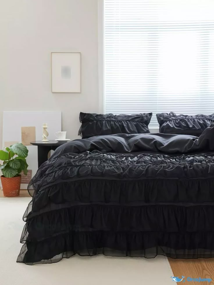 a bed with black ruffled bedspread and pillows in a room next to a window