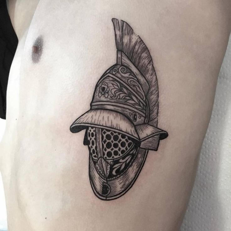 a woman's thigh with a tattoo on it that has a helmet and feathers