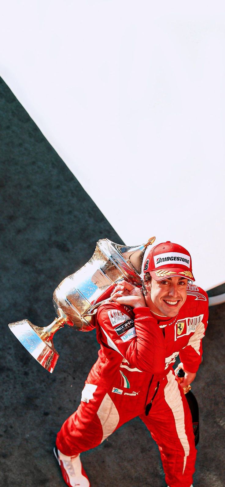 a man in red racing suit carrying a trophy on his back and smiling at the camera