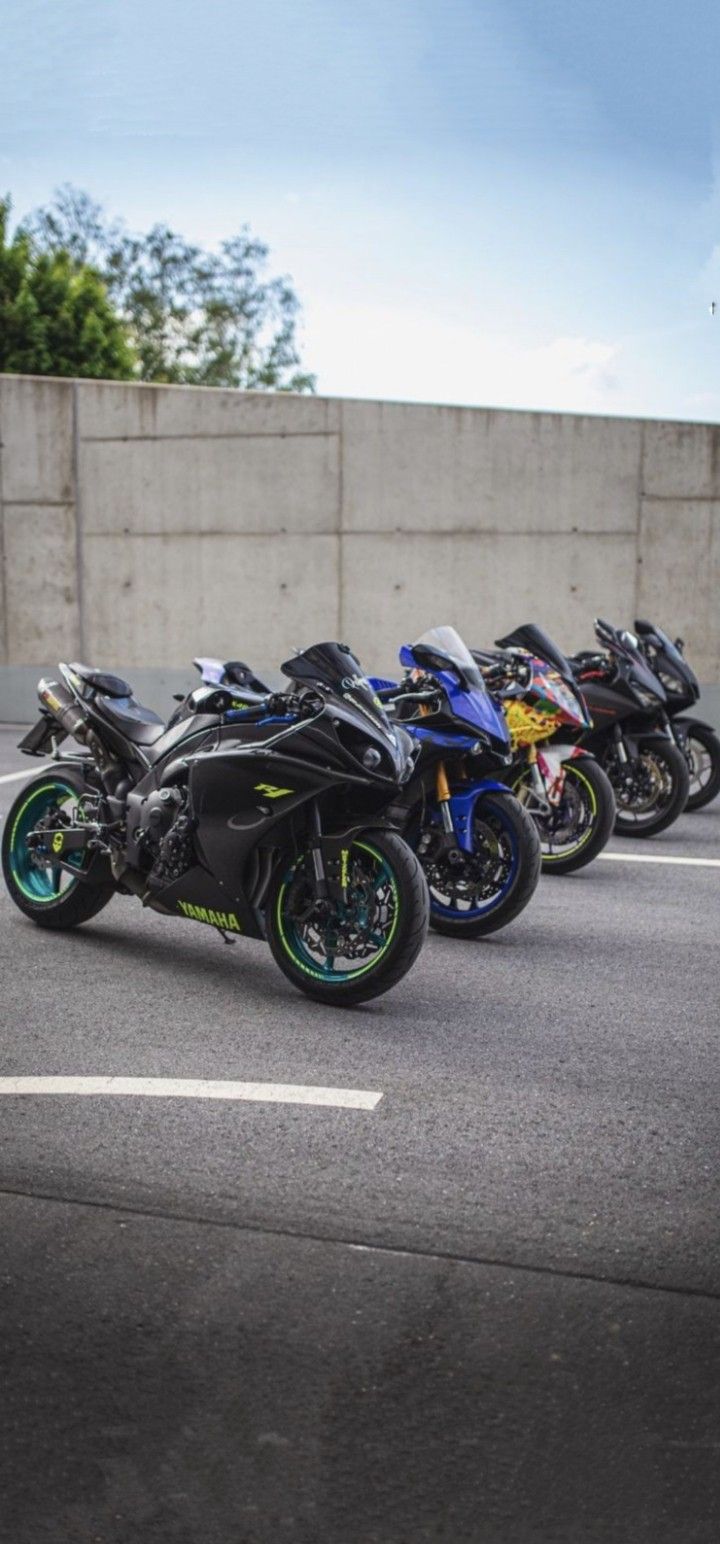 there are many motorcycles parked on the side of the road in front of a concrete wall