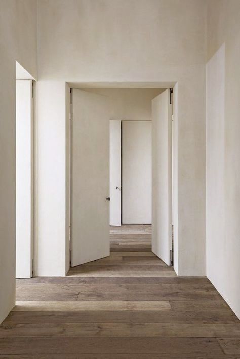 an empty hallway with white walls and wooden floors is seen in this image from the inside