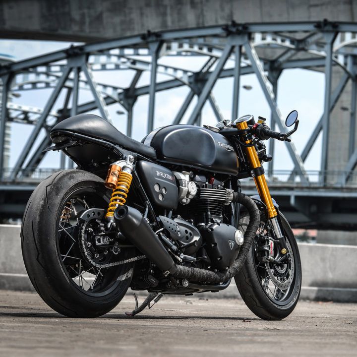 a black motorcycle parked in front of a bridge