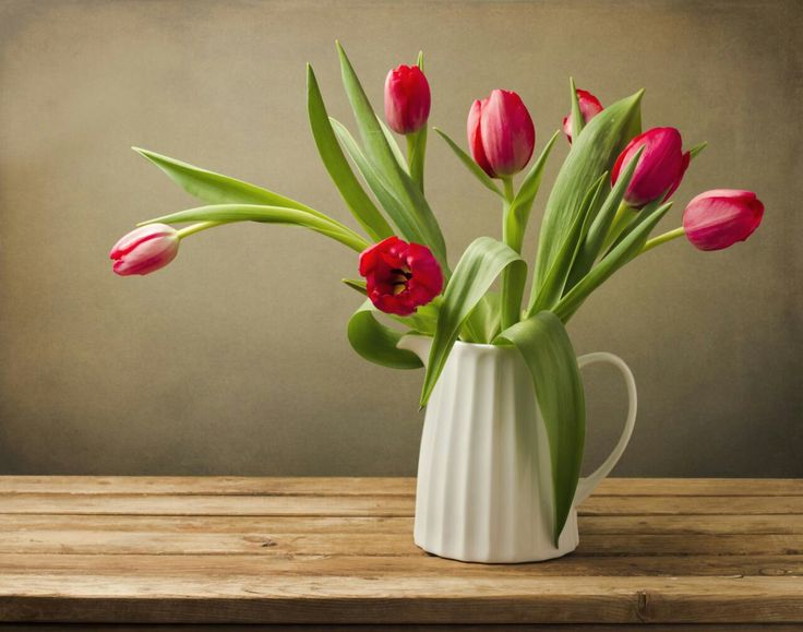 a vase filled with red tulips on top of a wooden table