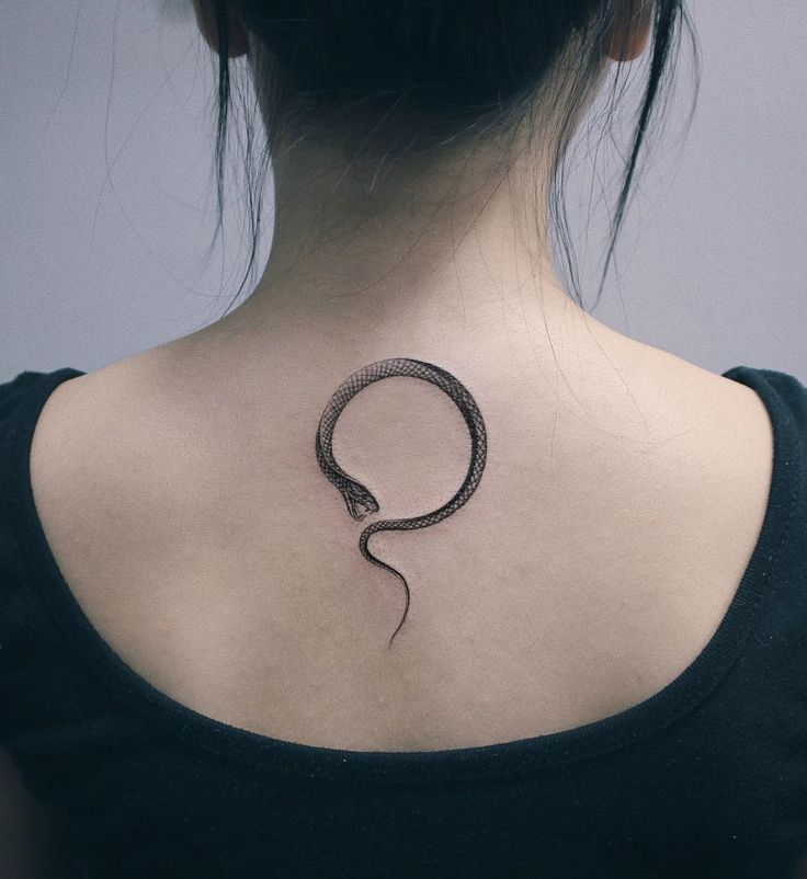 a woman's back neck with a snake tattoo on the upper part of her body