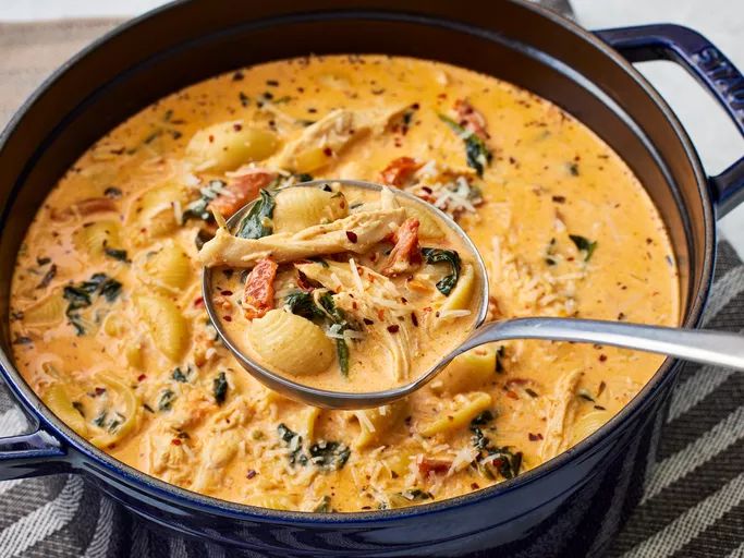 a ladle full of soup sitting on top of a blue pot filled with food