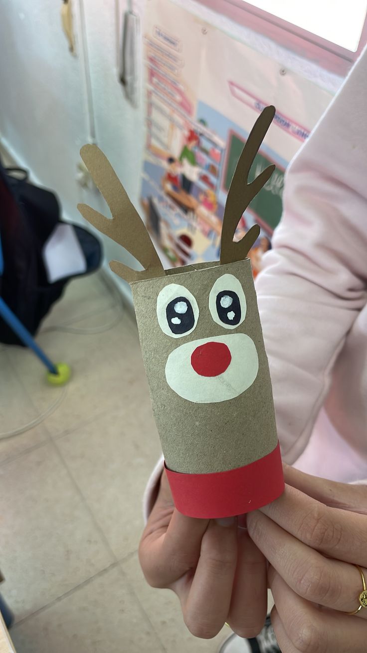 a person holding up a toilet paper roll with a reindeer face on it