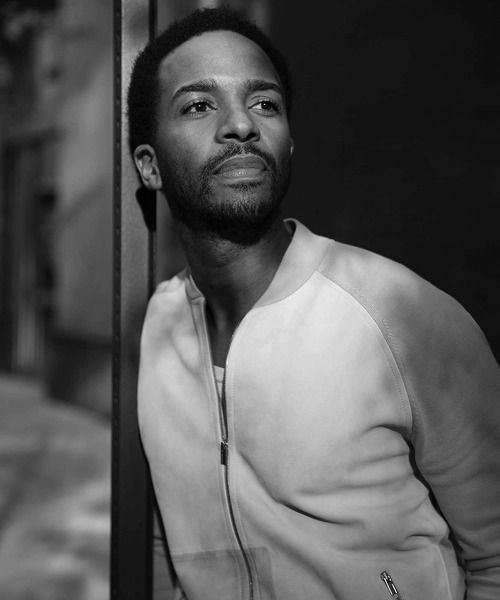 a man leaning against a pole on the street