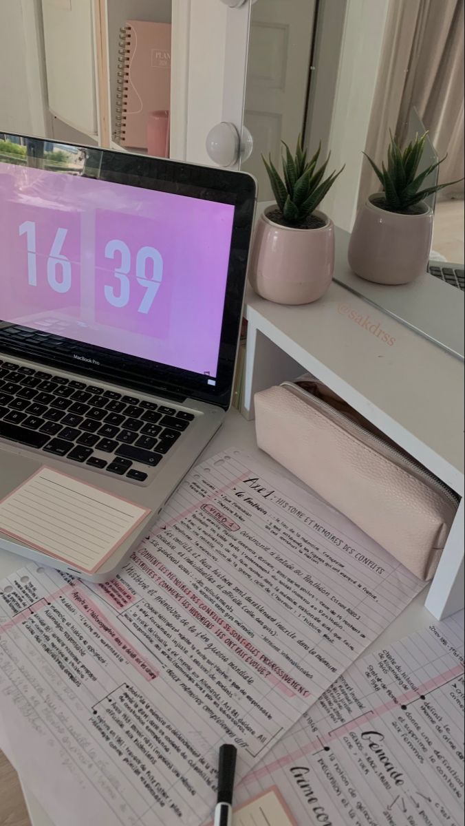 an open laptop computer sitting on top of a desk next to a pile of papers