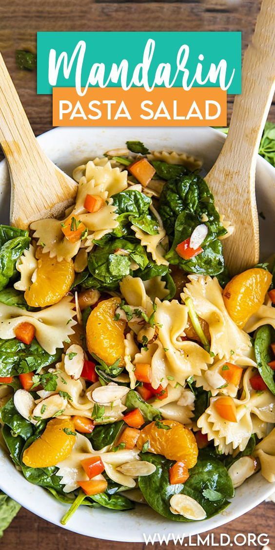 pasta salad with spinach and oranges in a white bowl