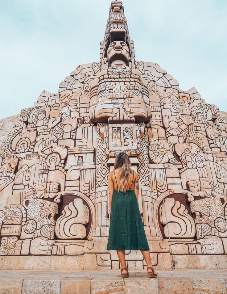 a woman standing in front of a building made out of carved stone with carvings on it