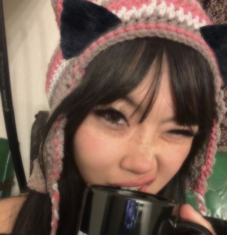 a woman wearing a knitted hat and holding a coffee mug