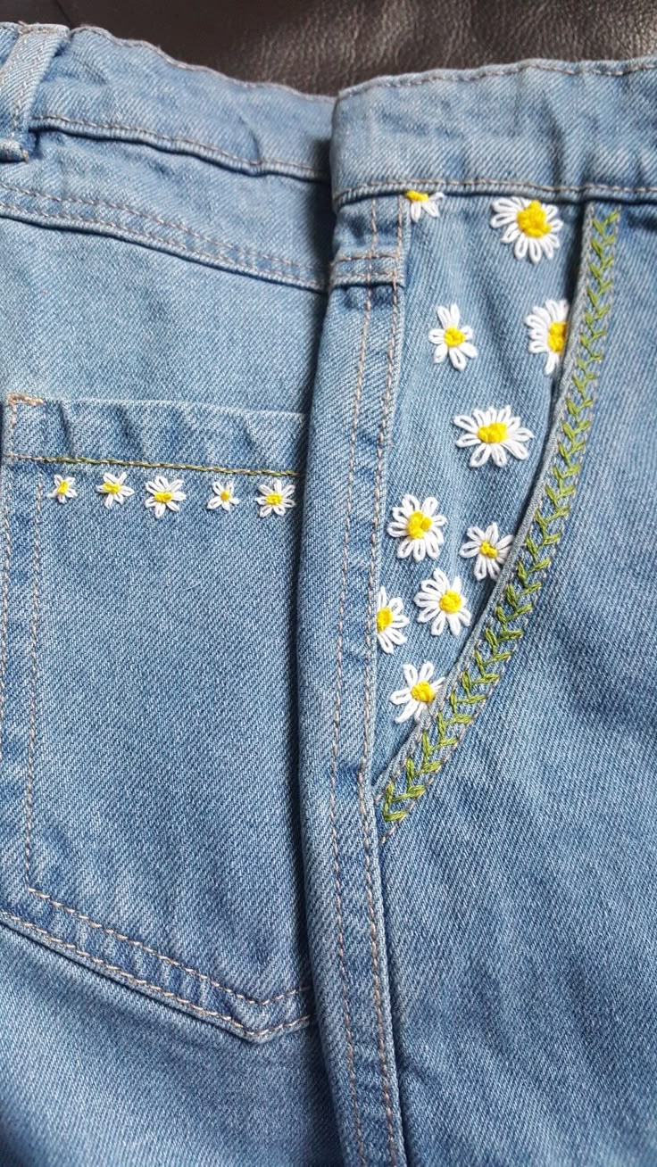 a pair of jeans with daisies embroidered on them