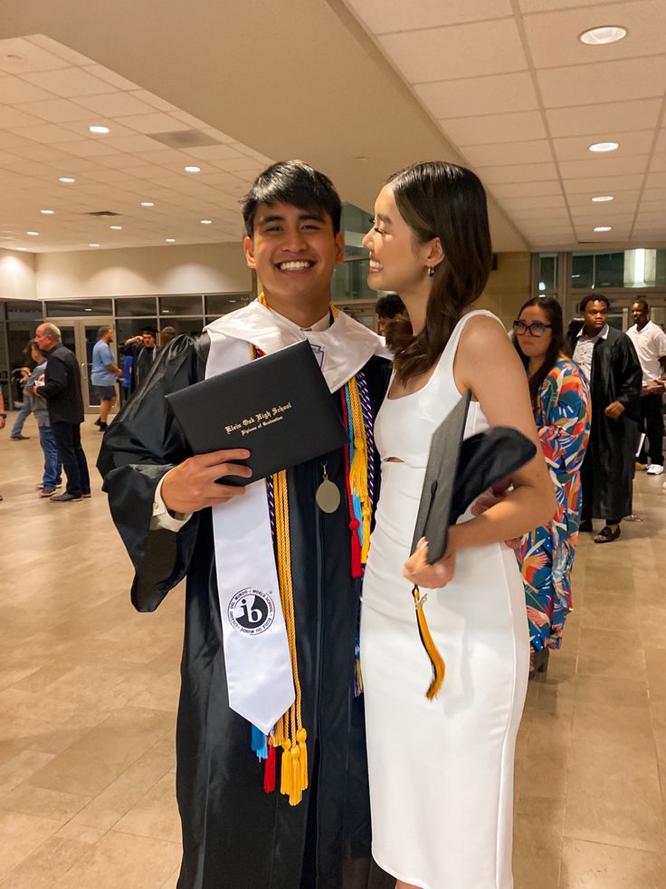 a man and woman standing next to each other in graduation regalinements at an event