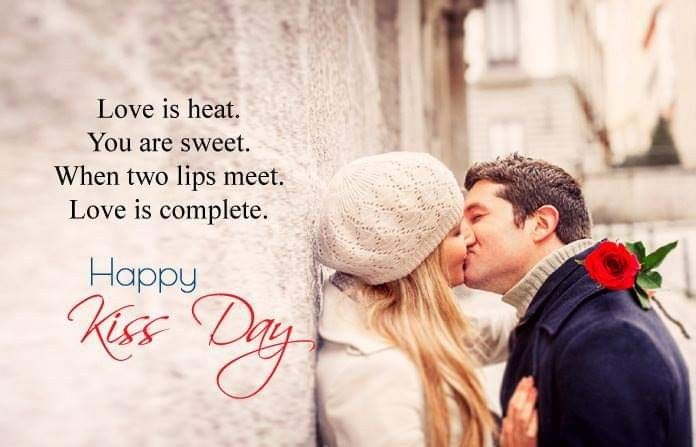 a man and woman kissing in front of a wall with the words happy kiss day written on it