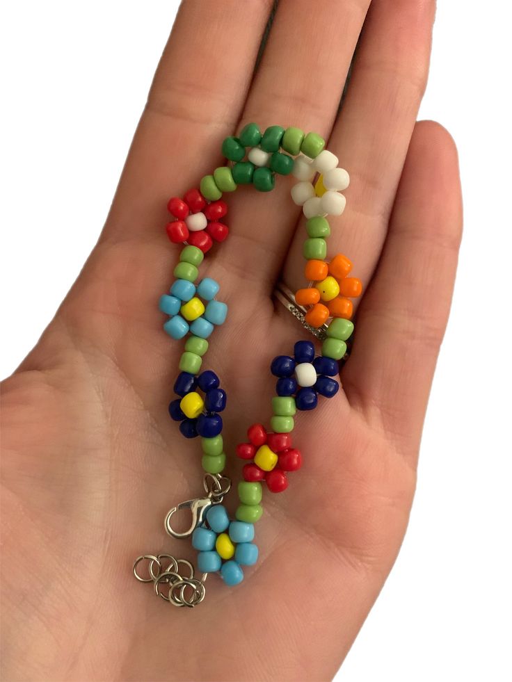 a hand holding a multi - colored beaded necklace with charms on it's fingers