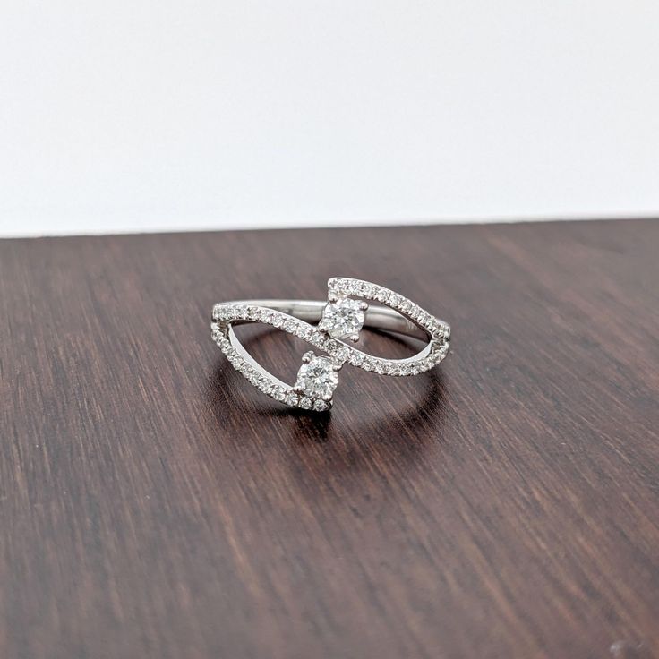 This dual diamond ring features a gorgeous a unique bypass design with natural earth mined diamonds set in solid 14K gold. This two stone diamond ring ring makes a lovely April birthstone gift for your loved ones! This ring is made with solid 14K Gold and natural Earth mined SI / G-H diamonds. As listed, this ring is ready to ship. If you're interested in purchasing this setting with a different center stone please message us! Fine Jewelry Bypass Ring With Tension Setting For Promise, Moissanite Open Ring For Anniversary, Sterling Silver Brilliant Cut Bypass Promise Ring, Sterling Silver Bypass Ring With Brilliant Cut For Promise, Diamond White Sterling Silver Bypass Promise Ring, Sterling Silver Bypass Ring For Promise, Fine Jewelry Bypass Promise Ring, White Gold Cubic Zirconia Bypass Promise Ring, Diamond White Cubic Zirconia Bypass Promise Ring