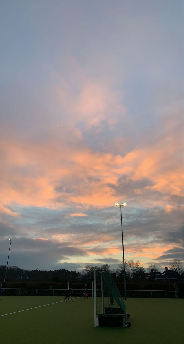 a soccer field at sunset with the sky in the background