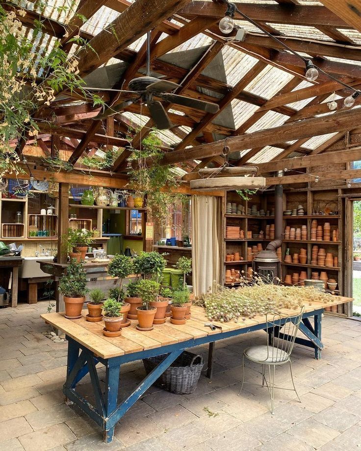 a table with potted plants on it in a room filled with wooden shelves and windows