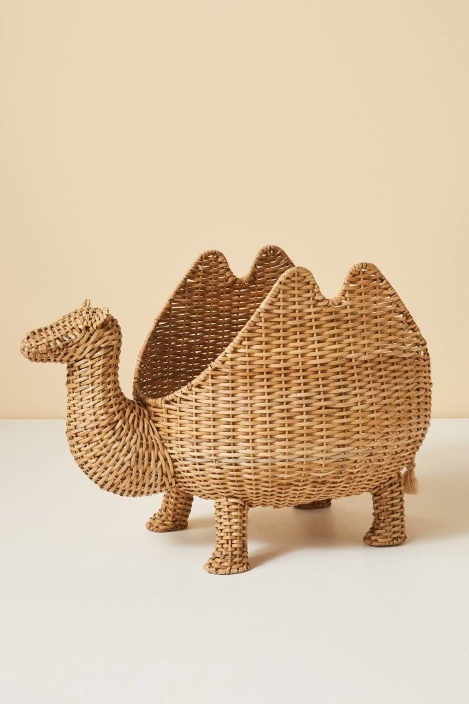 a small wicker camel figurine sitting on top of a white table next to a beige wall