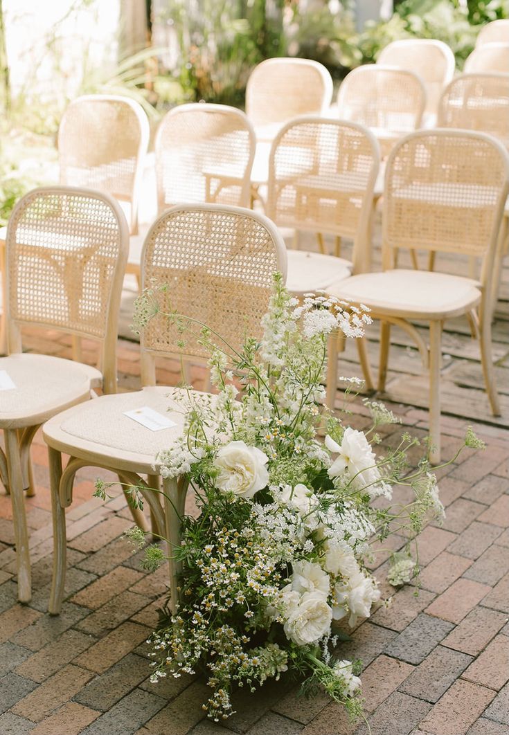 a bunch of chairs that are sitting on the ground with some flowers in them,