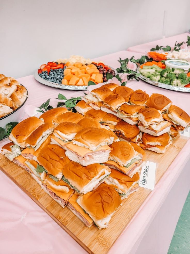 a table topped with lots of sandwiches and salads next to plates of appetizers