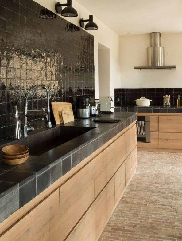 a kitchen with black counter tops and wooden cabinets in front of a painting on the wall