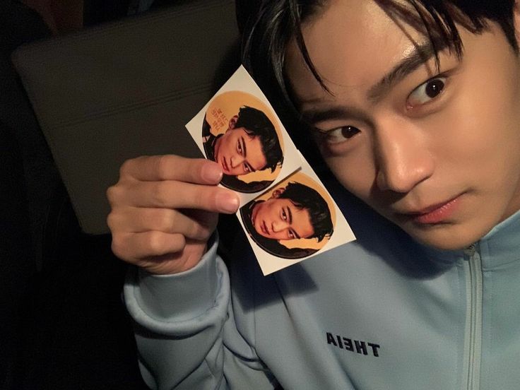 a man holding up two photos of himself