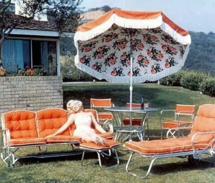 a woman sitting on top of a lawn chair next to an orange and white umbrella