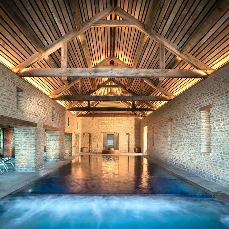 an indoor swimming pool with water running through the floor and wooden beams on the ceiling