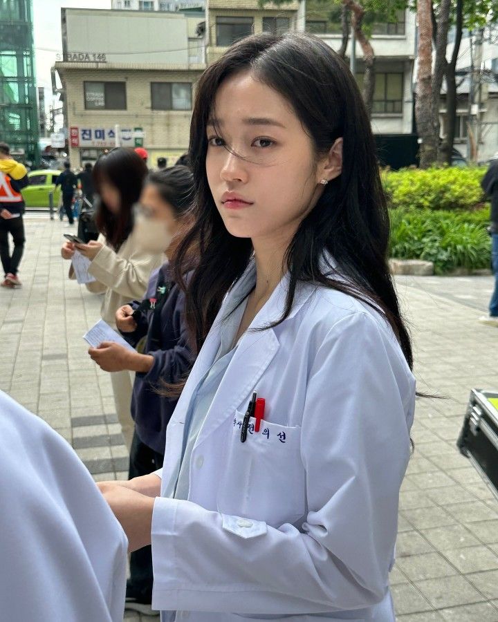 a woman in white lab coat standing on sidewalk