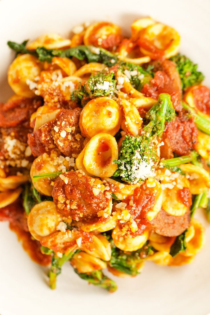 a white bowl filled with pasta and veggies on top of a wooden table