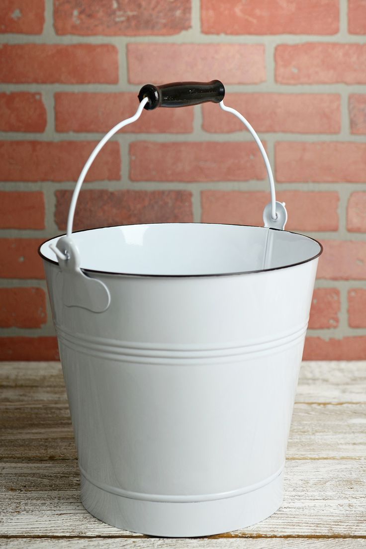 a white bucket sitting on top of a wooden table next to a red brick wall