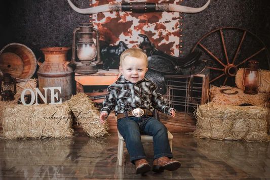 a young boy sitting on top of a wooden chair in front of hay bales