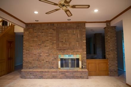 an empty living room with a fireplace and ceiling fan