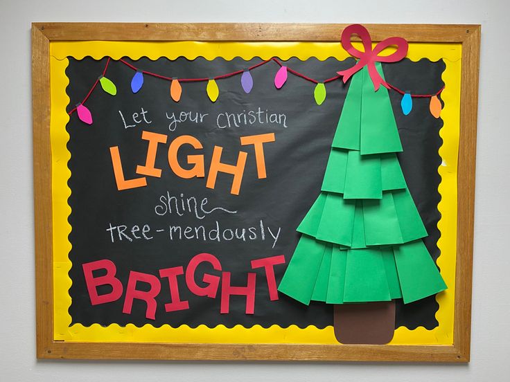 a christmas tree made out of paper on a blackboard with lights strung around it