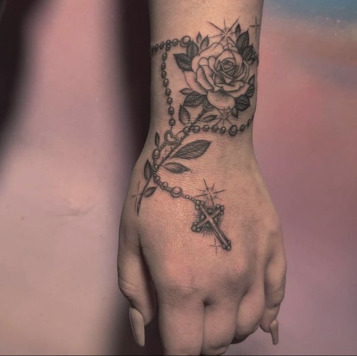 a woman's hand with a rosary and rose tattoo on it