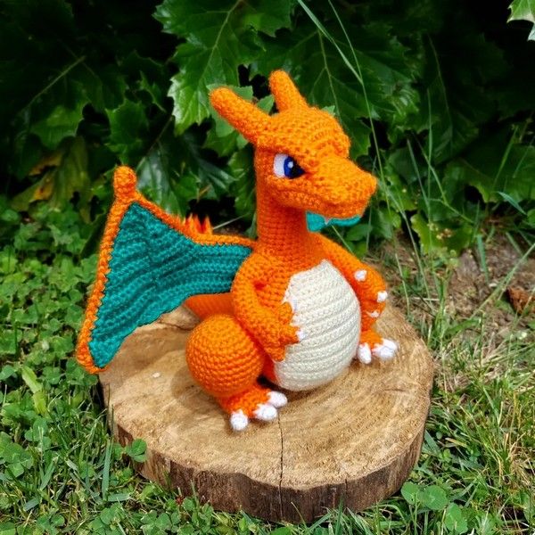 a crocheted dragon sitting on top of a tree stump