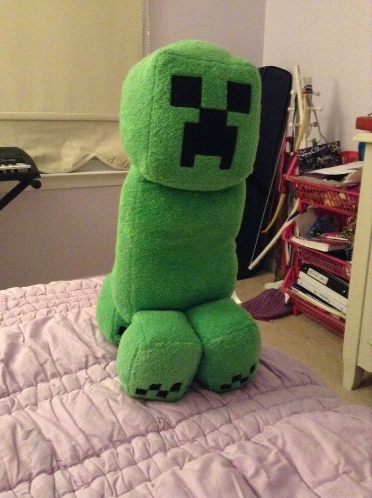 a green stuffed animal sitting on top of a bed