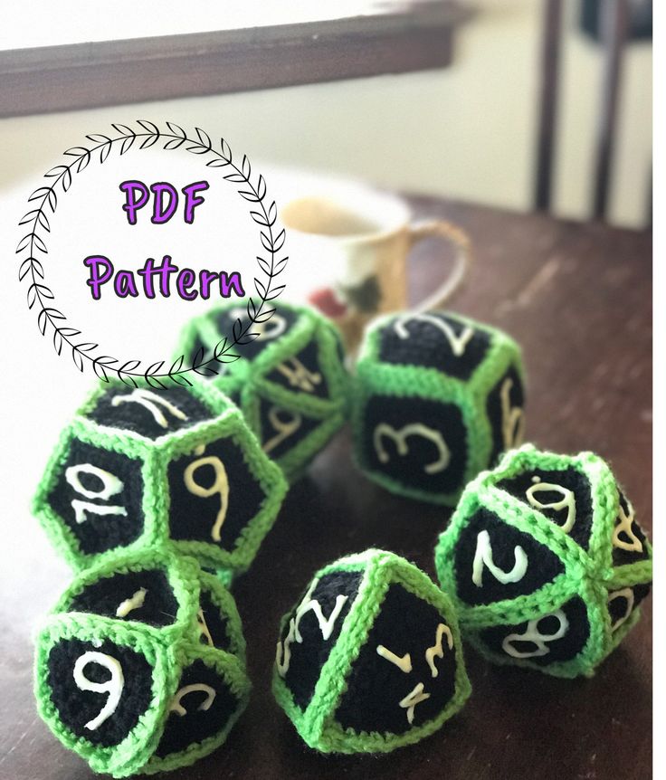 green and black crocheted dices with numbers on them sitting on a table