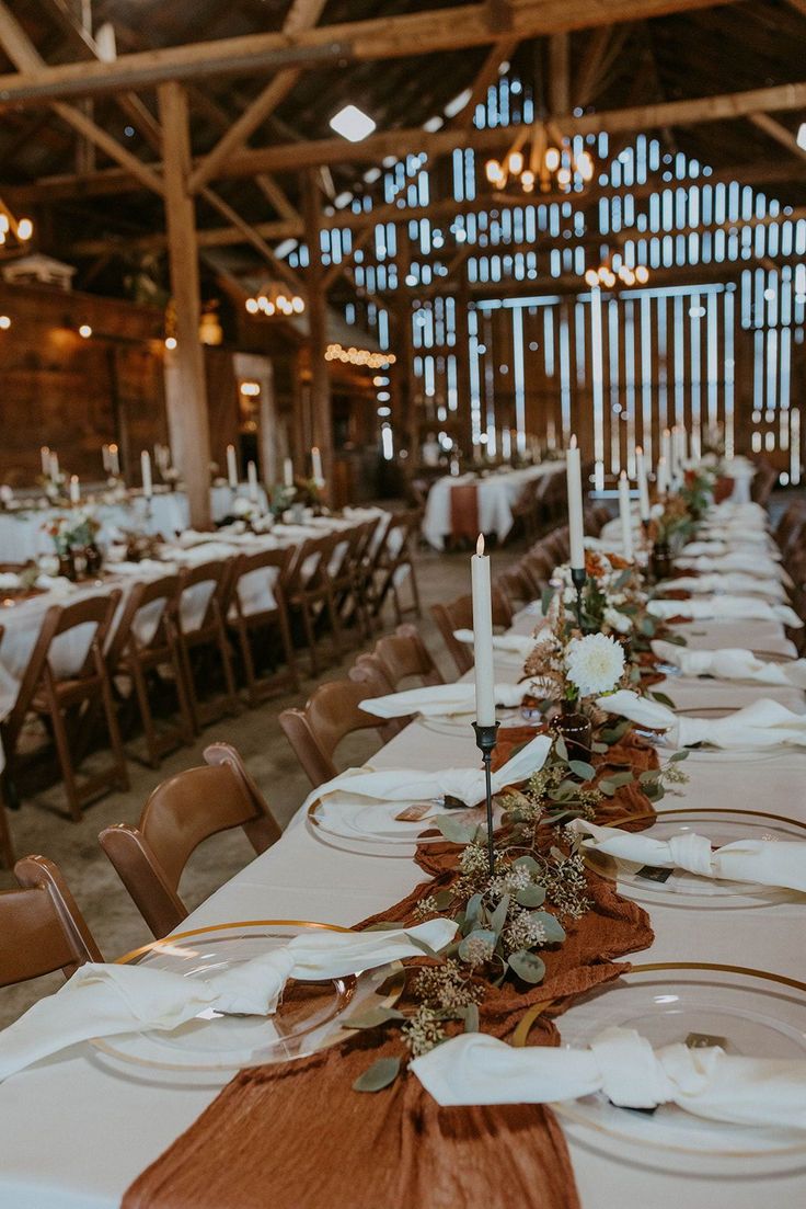 the tables are set with white and brown linen napkins, silverware, and candles