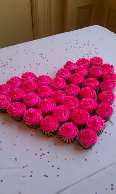 heart shaped cupcakes are arranged in the shape of a heart on a table