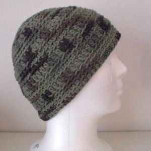 a white mannequin head wearing a green and brown knitted beanie hat